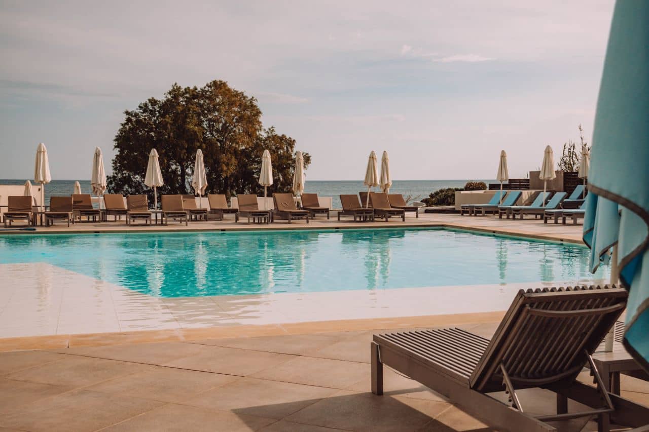 Liegen und Schirme stehen um den türkisblauen Pool des I Resort Beach Hotel auf Kreta.
