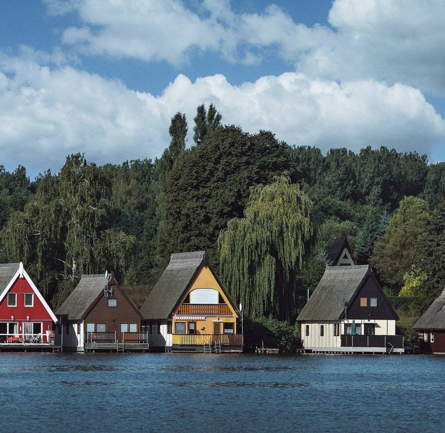 Einige kleine Häuschen direkt am Ufer eines Sees der Seenplatte Mecklenburg-Vorpommern.
