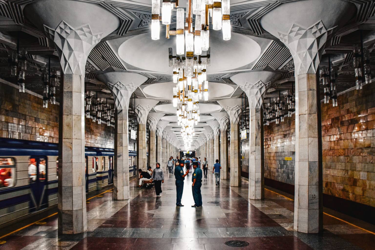 Innenansicht der Mustaqillik-Maydoni Metrostation in Taschkent mit hohen Säulen und dekorativen Leuchten
